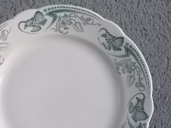 Assiette plate "Lucy", en faïence Ivoire. Décors en camaïeu de Vert. Motif de fleur grimpante type Clématite. Bordure festonnée. De la faïencerie K & G Lunéville