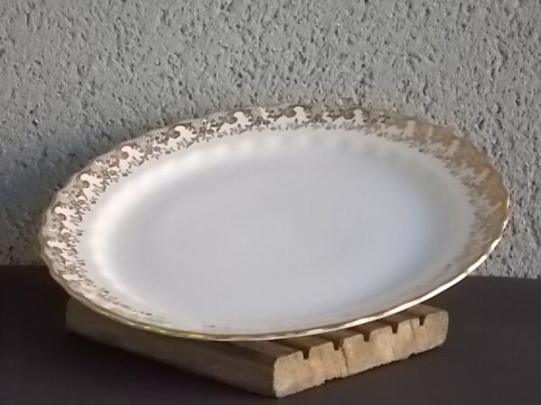 Assiette plate en porcelaine Blanche. Décors en bordure d'une frise en dorure et aile festonnée. De la marque Vitriam Saint Amand