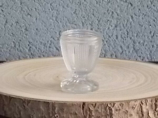 Coquetier à pied en verre épais translucide soufflé moulé. Décors alterné de bande lisse et double stries. Pied en quartier formant fleur.