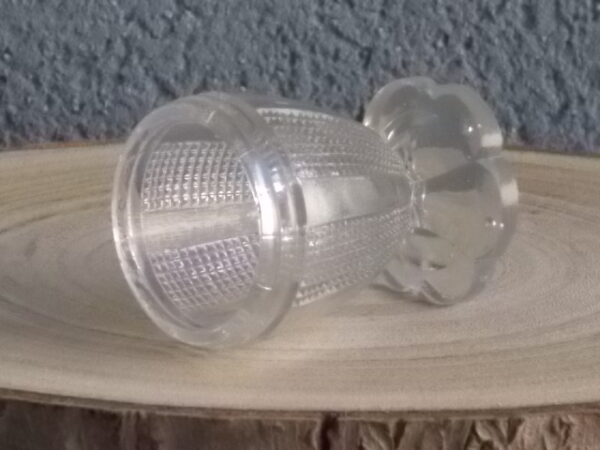 Coquetier à pied en verre épais translucide soufflé moulé. Décors alterné de bande lisse et double stries. Pied en quartier formant fleur.