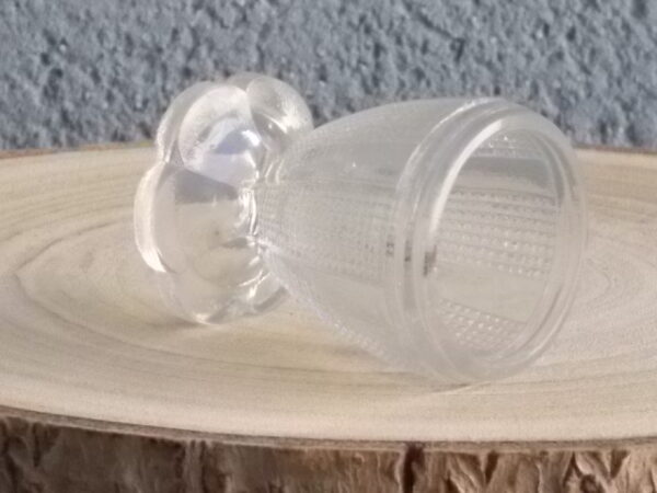 Coquetier à pied en verre épais translucide soufflé moulé. Décors alterné de bande lisse et double stries. Pied en quartier formant fleur.