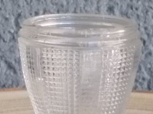 Coquetier à pied en verre épais translucide soufflé moulé. Décors alterné de bande lisse et double stries. Pied en quartier formant fleur.
