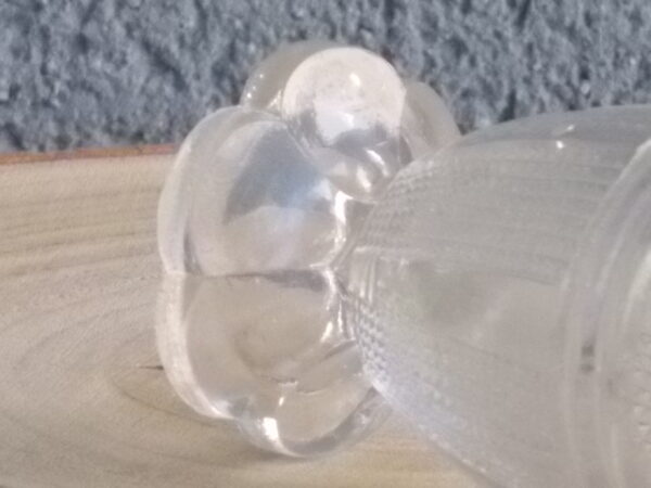 Coquetier à pied en verre épais translucide soufflé moulé. Décors alterné de bande lisse et double stries. Pied en quartier formant fleur.