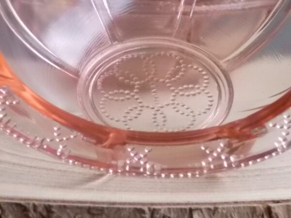Coupelle en verre teinté Rose Saumoné, moulé pressé. Bol à rebord perlé plat avec effet piliers de soutient. Base fond cercles entrelacés perlés.