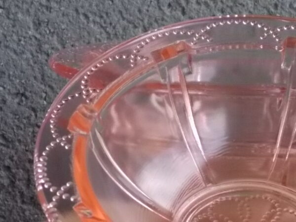 Coupelle en verre teinté Rose Saumoné, moulé pressé. Bol à rebord perlé plat avec effet piliers de soutient. Base fond cercles entrelacés perlés.