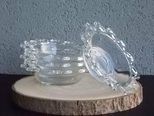 Coupelle ronde en verre translucide à bordure plate ajourée, moulé pressé. Coté biaisé, fond effet martelé avec motif forme de la coupelle.