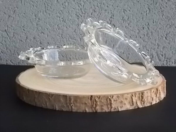Coupelle ronde en verre translucide à bordure plate ajourée, moulé pressé. Coté biaisé, fond effet martelé avec motif forme de la coupelle.