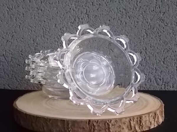 Coupelle ronde en verre translucide à bordure plate ajourée, moulé pressé. Coté biaisé, fond effet martelé avec motif forme de la coupelle.