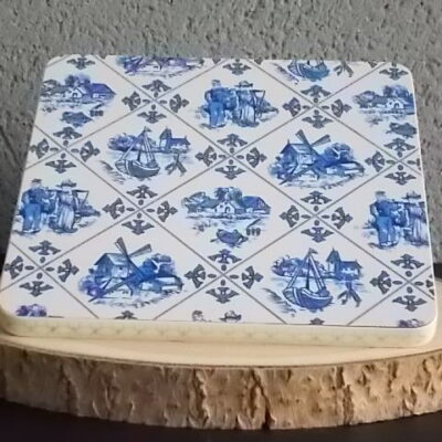 Dessous de plat "Hollande" en Formica sur aggloméré, à motif Bleu sur fond Blanc. Quatre pieds plastique Blanc en demi cercle