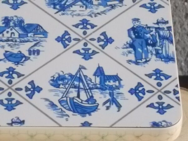 Dessous de plat "Hollande" en Formica sur aggloméré, à motif Bleu sur fond Blanc. Quatre pieds plastique Blanc en demi cercle