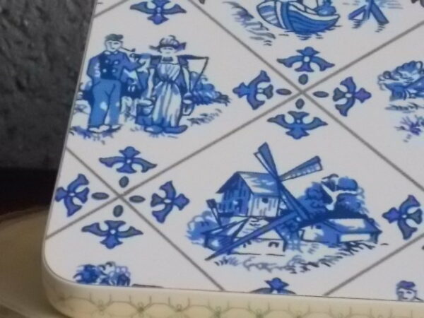 Dessous de plat "Hollande" en Formica sur aggloméré, à motif Bleu sur fond Blanc. Quatre pieds plastique Blanc en demi cercle