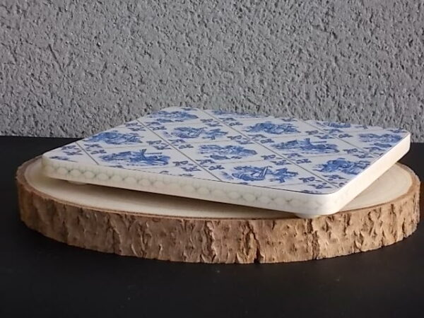 Dessous de plat "Hollande" en Formica sur aggloméré, à motif Bleu sur fond Blanc. Quatre pieds plastique Blanc en demi cercle