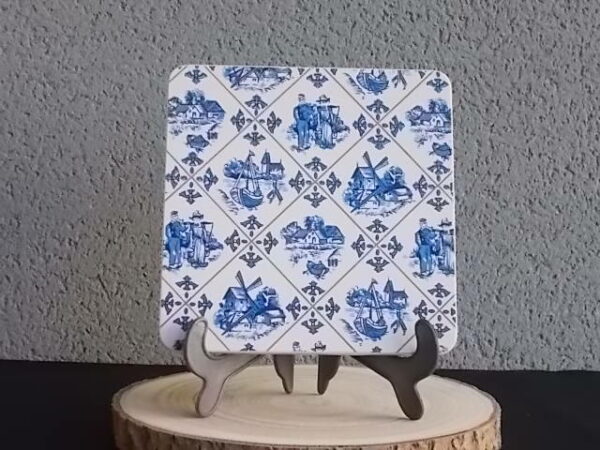 Dessous de plat "Hollande" en Formica sur aggloméré, à motif Bleu sur fond Blanc. Quatre pieds plastique Blanc en demi cercle