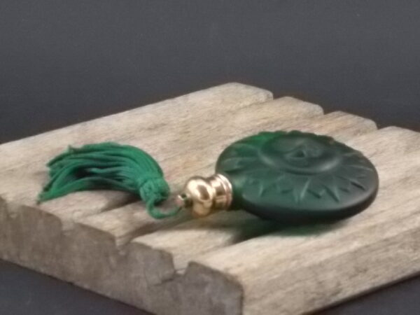 Flacon de Parfum de sac, en pate de verre Vert. Motif en relief "Visage Soleil". Bouchon en métal Doré, avec Pompon Gland Vert.