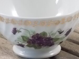 Petit bol piédouche "Bouquet de Violettes" en porcelaine Blanche torsadé à motif floral, et frise en dorure.