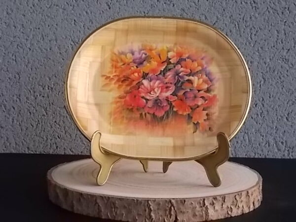 Petit plateau ovale creux, en tissage de feuille de Palmier vernissé, à décors imprimé fleurie. Bordure en cerclage de plastique Doré.