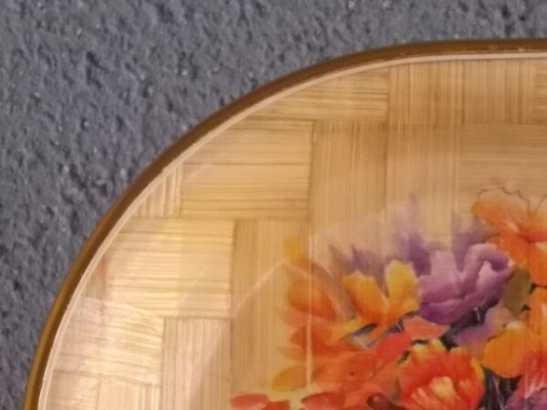 Petit plateau ovale creux, en tissage de feuille de Palmier vernissé, à décors imprimé fleurie. Bordure en cerclage de plastique Doré.