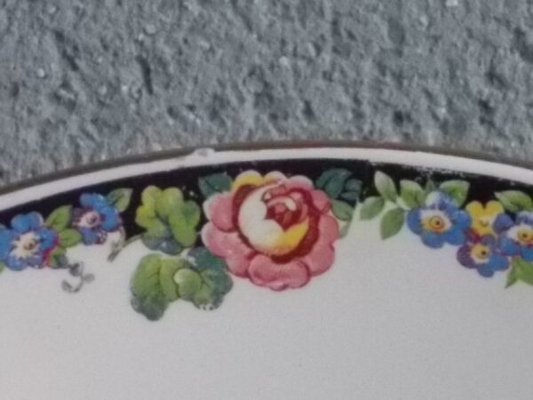 Plat creux rond "3984", en faience Blanche. Motif floral de fleurs Rose et Bleu alternée et feuillage Vert sur fond Noir. Liseré en dorure sur bordure. De la faïencerie de Sarreguemines France.