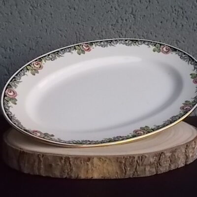 Plat ovale creux "3984", en faience Blanche. Motif floral de fleurs Rose et Bleu alternée et feuillage Vert sur fond Noir. Liseré en dorure sur bordure. De la faïencerie de Sarreguemines France.