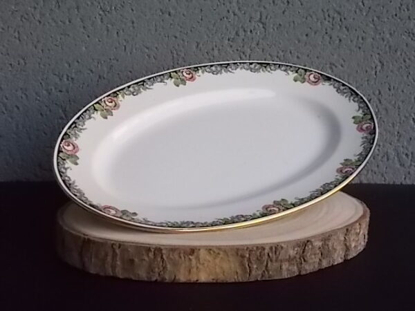 Plat ovale creux "3984", en faience Blanche. Motif floral de fleurs Rose et Bleu alternée et feuillage Vert sur fond Noir. Liseré en dorure sur bordure. De la faïencerie de Sarreguemines France.