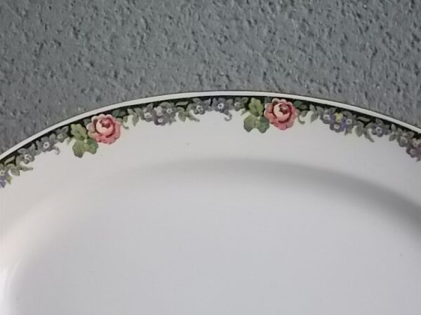 Plat ovale creux "3984", en faience Blanche. Motif floral de fleurs Rose et Bleu alternée et feuillage Vert sur fond Noir. Liseré en dorure sur bordure. De la faïencerie de Sarreguemines France.