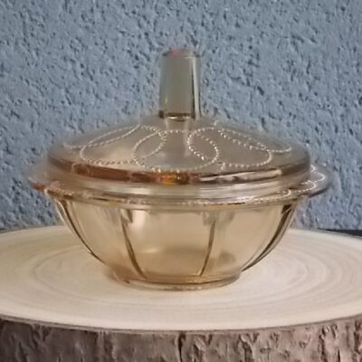 Sucrier couvert en verre teinté Ambre, moulé pressé. Bol à rebord perlé plat avec effet piliers de soutient. Base fond cercles entrelacés perlés. Couvercle Dôme, bouton conique.