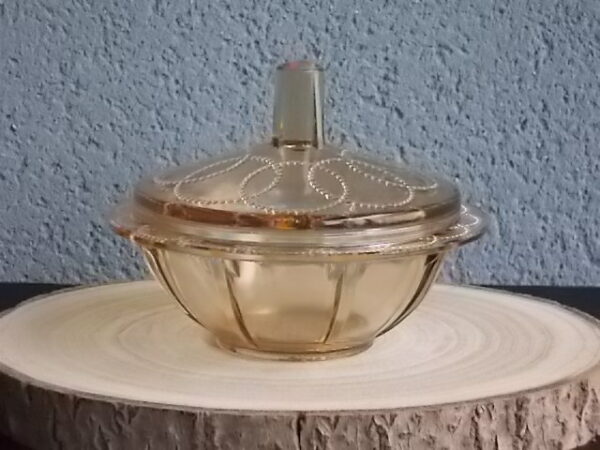Sucrier couvert en verre teinté Ambre, moulé pressé. Bol à rebord perlé plat avec effet piliers de soutient. Base fond cercles entrelacés perlés. Couvercle Dôme, bouton conique.