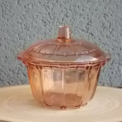 Sucrier couvert en verre teinté Rose Saumoné, moulé pressé. Bol tour cannelé nervuré. Rebord festonné perlé. Base fond Soleil pieds perlés. Couvercle Dôme, bouton conique.