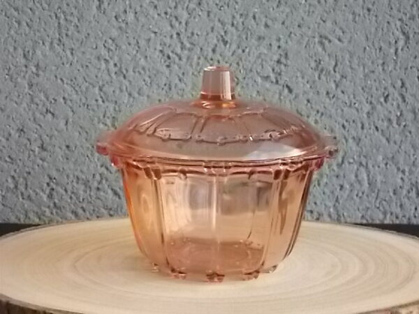 Sucrier couvert en verre teinté Rose Saumoné, moulé pressé. Bol tour cannelé nervuré. Rebord festonné perlé. Base fond Soleil pieds perlés. Couvercle Dôme, bouton conique.
