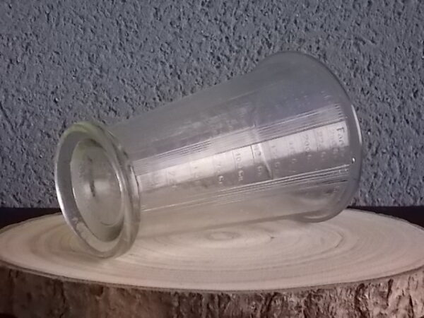 Verre doseur en verre épais translucide moulé pressé. Forme évasé sur base socle. Verre gradué contenant 300 gr. De Portieux Mougin Déposé.