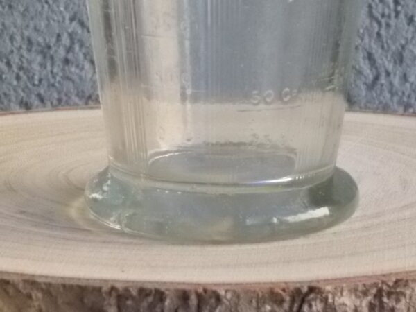 Verre doseur en verre épais translucide moulé pressé. Forme évasé sur base socle. Verre gradué contenant 300 gr. De Portieux Mougin Déposé.