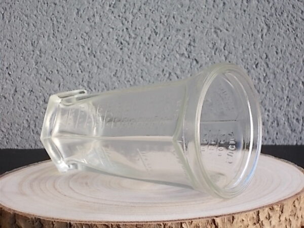 Verre doseur en verre translucide épais moulé. Forme évasé à cotes plates sur base socle Hexagonale. Graduation extérieur, et rebord épais.